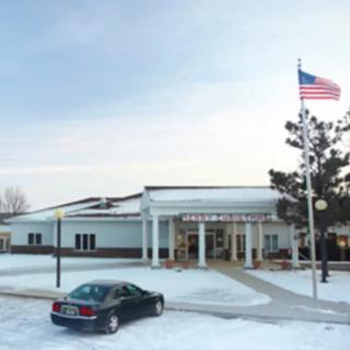 A building with an American flag, surrounded by snow and a parked car.