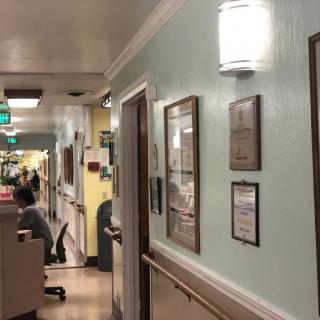 A hospital hallway with a nursing station and framed certificates on the wall.