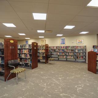 A quiet library interior with rows of bookshelves and seating areas.