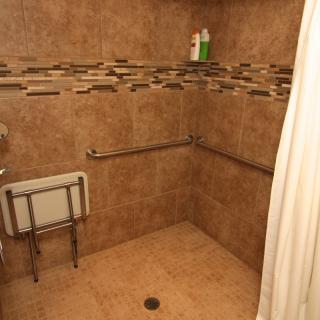 Accessible shower with grab bars and folding seat.