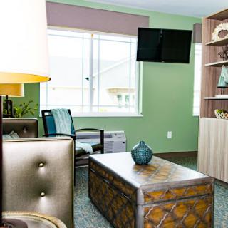 A modern living room featuring a stylish coffee table, comfortable seating, and a television against a soothing green backdrop.