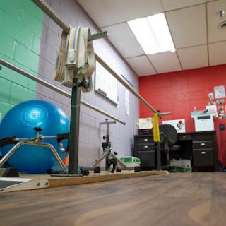 A well-equipped rehabilitation and exercise room featuring a balance ball and barre.