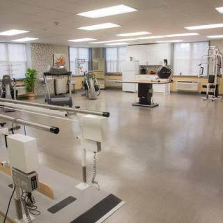 A spacious rehabilitation room equipped with various exercise machines and therapy equipment.