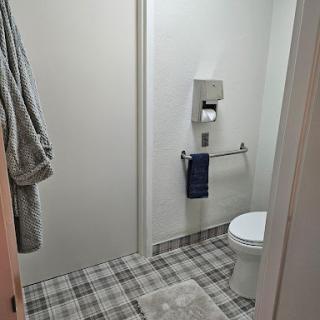 A simple and clean bathroom setup featuring a toilet, towel rack, and plaid flooring.