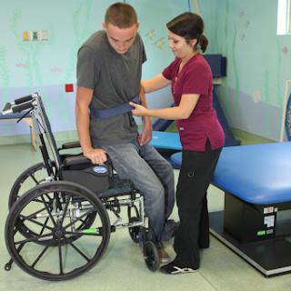 A healthcare professional assisting a patient in a wheelchair during a rehabilitation session.