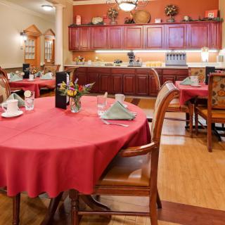 A cozy restaurant dining area with tables set for a meal, featuring red tablecloths and elegant decor.