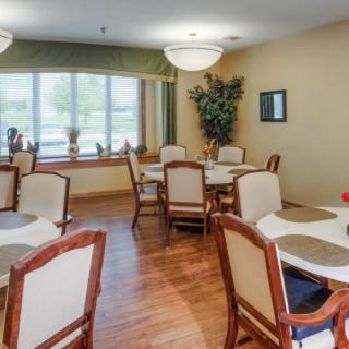 A cozy dining room with multiple tables and chairs, well-lit by natural light from the window.