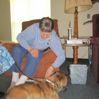A woman interacts with a dog in a cozy living room setting.
