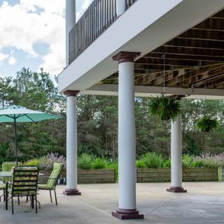 A spacious outdoor patio featuring columns and patio furniture under a clear sky.