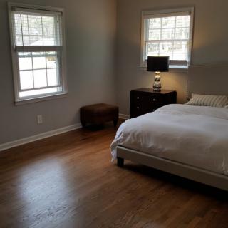 A minimalist bedroom with wooden flooring and simple furnishings.
