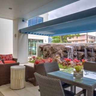 A cozy patio with comfortable seating, overlooking a lush garden and small waterfall.