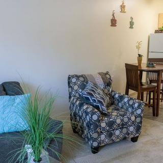 A cozy living room with a patterned armchair and sofa, adjacent to a dining area.