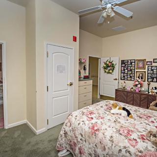 A cozy bedroom featuring floral bedding, photos on the wall, and a ceiling fan.