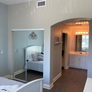 A bright bedroom with a mirrored closet and an attached vanity area.