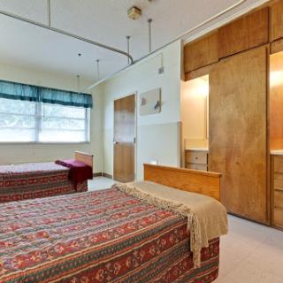 A cozy bedroom featuring two beds with patterned covers and warm wooden accents.