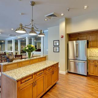 A modern kitchen with wooden cabinets, a granite countertop island, and stainless steel appliances.