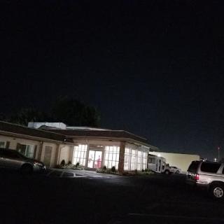 A nighttime view of a building with illuminated windows and parked cars in the foreground.