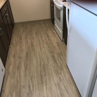 A modern kitchen with wooden flooring and appliances.