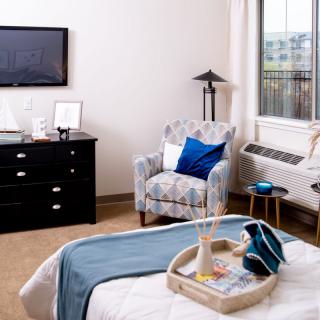 A cozy and modern bedroom featuring a comfortable armchair, sleek dresser, and stylish decor.