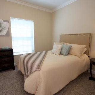 A cozy bedroom with a neatly made bed, soft lighting, and simple decor.