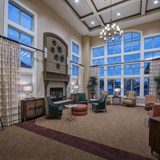 A spacious and cozy living room with large windows, a fireplace, and elegant furniture.