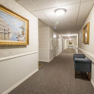 A well-lit hotel hallway featuring framed artwork and seating.