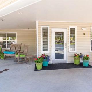 A welcoming porch area with colorful potted plants and seating outside a door.