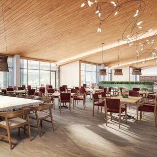 A modern restaurant interior with wooden ceilings and elegant lighting, featuring empty tables ready for dining.