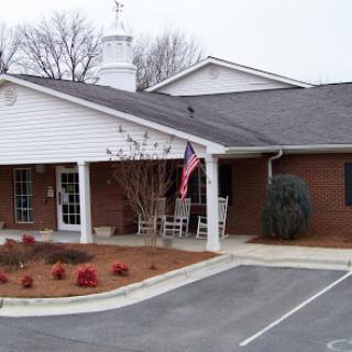 A charming one-story residential building adorned with a flag and surrounded by landscaped gardens.