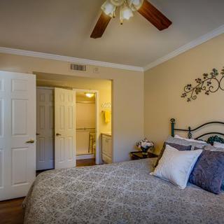 A cozy bedroom with a neatly made bed, ceiling fan, and stylish decor.