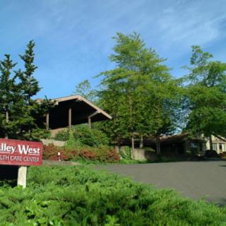 A scenic view of a winery surrounded by lush greenery and trees, with a sign in the foreground.