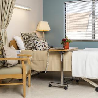 A comfortable and well-equipped hospital room with a bed, chair, and bedside table.