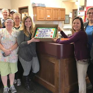 A team gathering to celebrate a special occasion with cake.