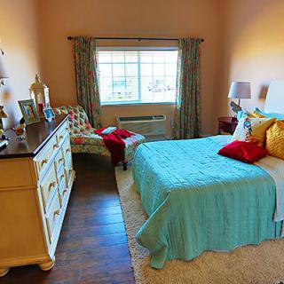 A cozy and colorful bedroom with a bed, dresser, and window.