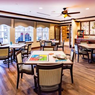 A modern dining area featuring several tables and chairs with large windows and wooden flooring.