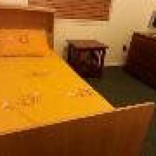 A cozy bedroom with a yellow bedspread and wooden furniture.