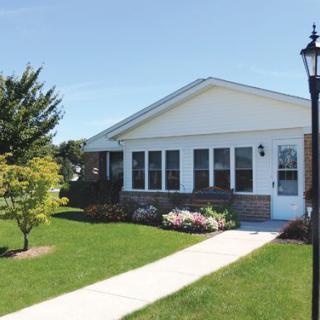 A suburban house with a well-maintained lawn and pathway on a sunny day.