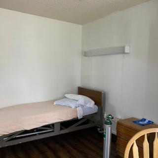 A simple hospital room with a single adjustable bed and minimal furnishings.