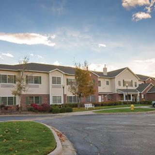 A suburban residential apartment complex with a driveway and landscaped surroundings.