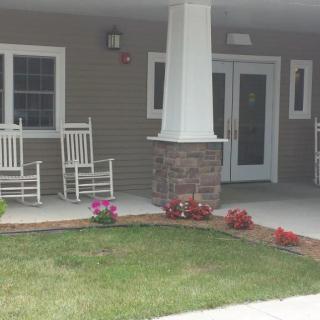 A cozy porch with rocking chairs and colorful flowers near the entrance.