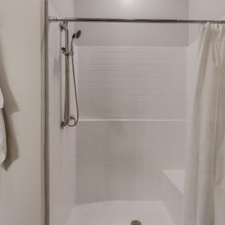 A bathroom with a shower area featuring a curtain and towel.