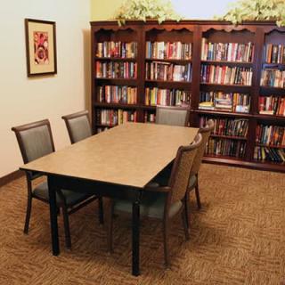 A cozy library corner with bookshelves, a table, and chairs for reading and study.