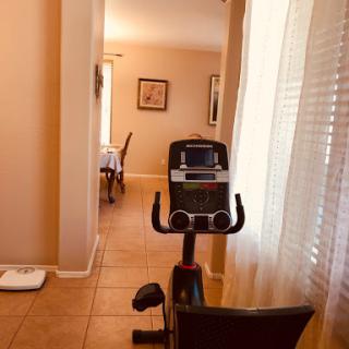 A view of a stationary exercise bike positioned in a well-lit indoor space, leading to a dining area.