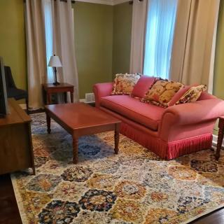 A cozy living room with a red sofa, wooden coffee table, and a patterned rug.