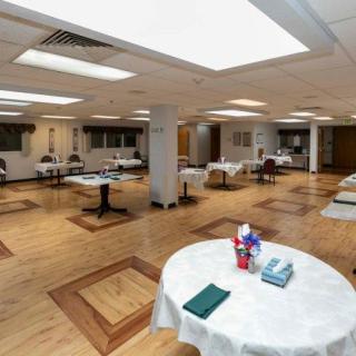 A spacious dining area with multiple round tables and chairs set up indoors.