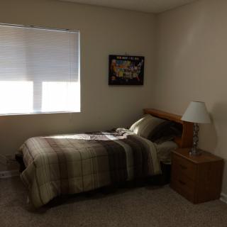 A minimalist bedroom with a single bed, nightstand, and lamp.
