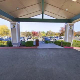 A covered driveway entrance with a view of the parking lot and trees in the background.
