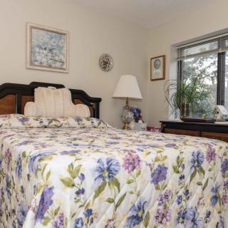 A cozy bedroom with a floral bedspread and decorative elements by the window.