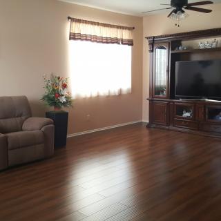 A cozy living room with a recliner, hardwood floors, and entertainment center featuring a large television.