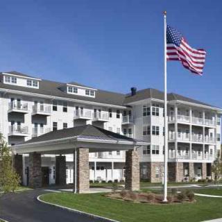 A residential building with an American flag flying in front on a sunny day.